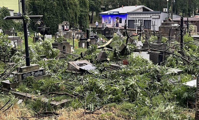 cmentarz i zniszczone nagrobki, przeszła nawałnica, duży wiatr. W oddali widać drzewa, bloki i niebo