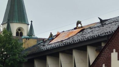 Dach kościoła, oderwana blacha po przejściu nawałnicy, strażacy na dachu